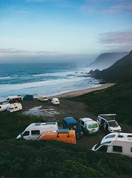 A group of campers parked on the side of a beach.