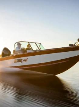 A boat is traveling on the water at sunset.