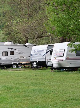 A group of recreational vehicles parked in the grass.